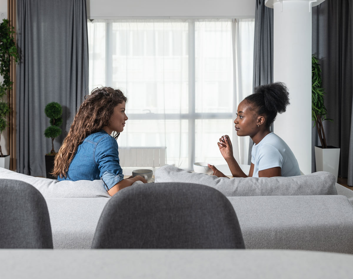 two women talking on a couch